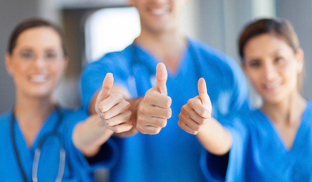 Three Nurses in Scrubs Giving Thumbs Up